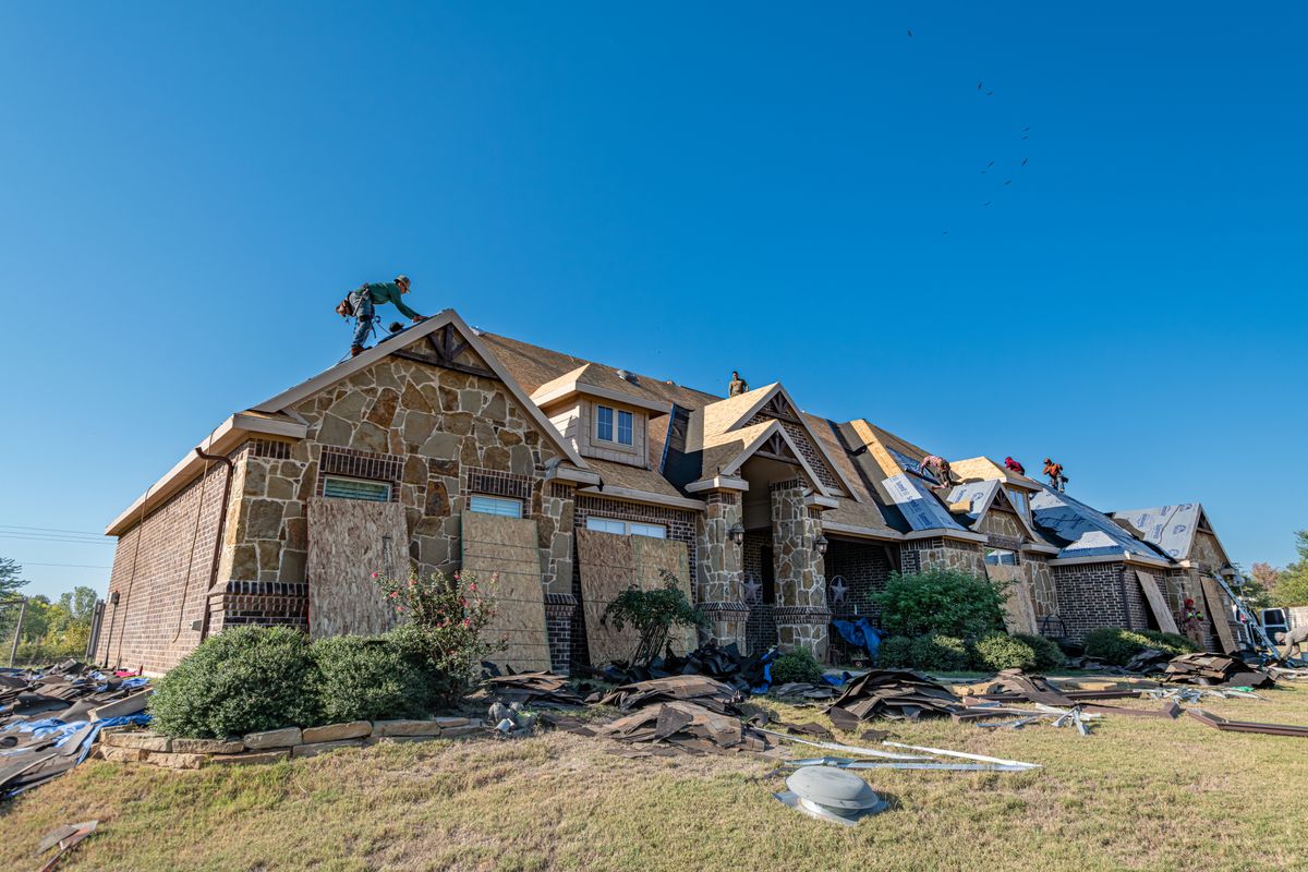A brick house during roof replacement with the work area visible