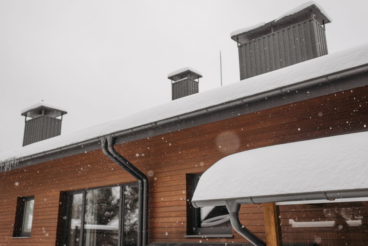 Snow falling around a roof edge, gutters, and roof vents